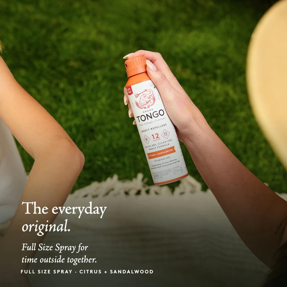An adult holds Citrus + Sandalwood Full Size Spray beside a child’s exposed arm. The everyday original. Full Size Spray for time outside together.