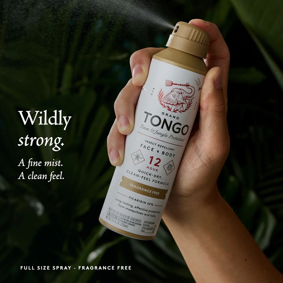 A hand sprays genuine Fragrance Free Full Size Spray against dark jungle foliage. Wildly strong. A fine mist. A clean feel.