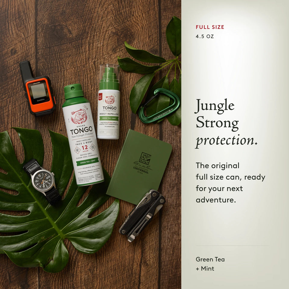 Grand Tongo Green Tea + Mint Full Size Spray, 4.5 oz and a matching travel spray in an outdoor gear flat lay with a radio, carabiner, compass, notebook, and multitool. The scene shows range context, not the quantity included in the selected product. Jungle Strong protection. The original full size can, ready for your next adventure.