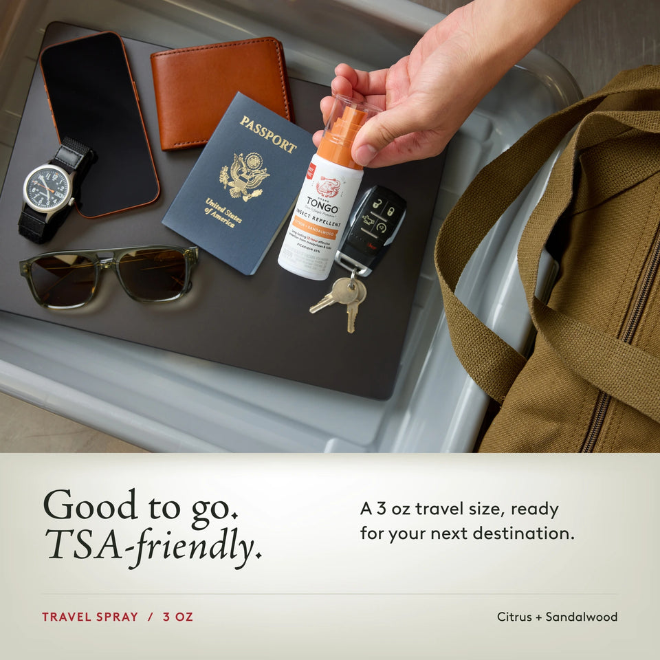 Grand Tongo Citrus + Sandalwood Travel Pump Spray, 3 oz held over a travel tray alongside a passport, phone, wallet, watch, sunglasses, keys, and bag. Good to go. TSA-friendly. A 3 oz travel size, ready for your next destination.
