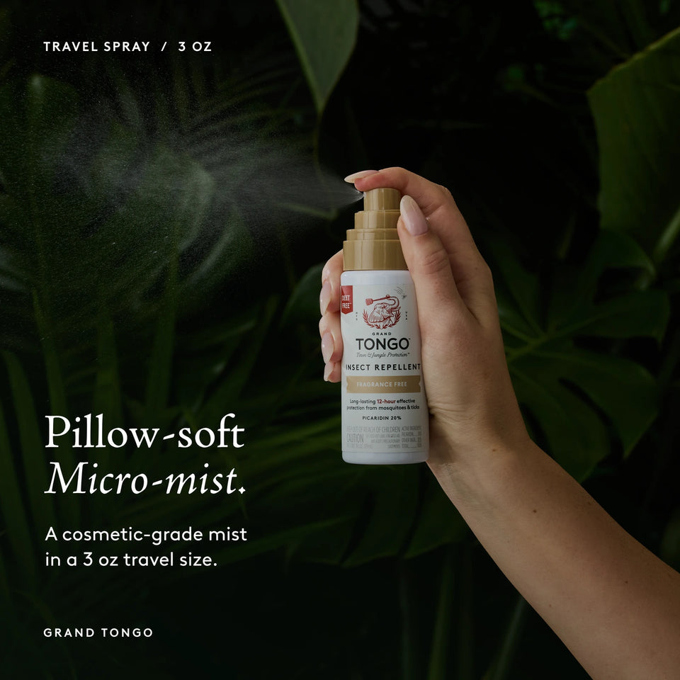 Grand Tongo Fragrance Free Travel Pump Spray, 3 oz held in a hand, dispensing a visible mist against dark green foliage. Pillow-soft Micro-mist. A cosmetic-grade mist in a 3 oz travel size.