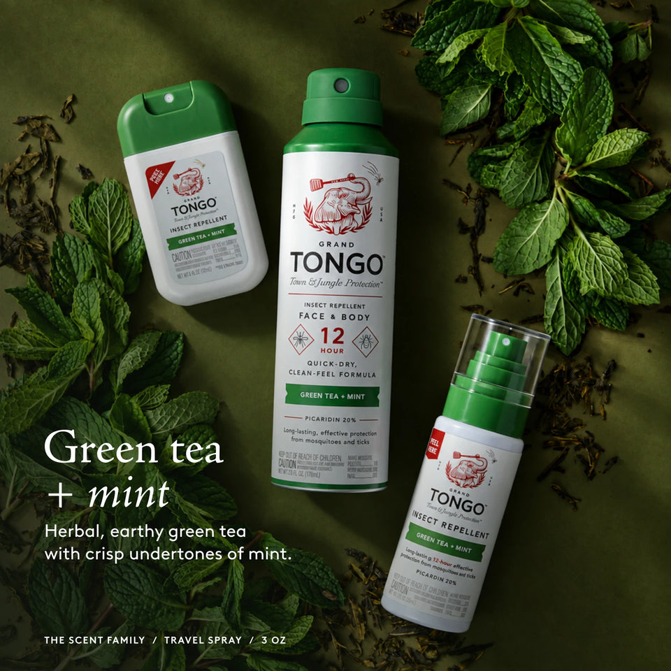 The Grand Tongo Green Tea + Mint scent family: full-size, travel, and pocket sprays arranged on green foliage, loose tea, and mint leaves. This is a scent-family image, not the quantity included in the selected product. Green tea + mint. Herbal, earthy green tea with crisp undertones of mint. The scent family / Travel Pump Spray / 3 oz.